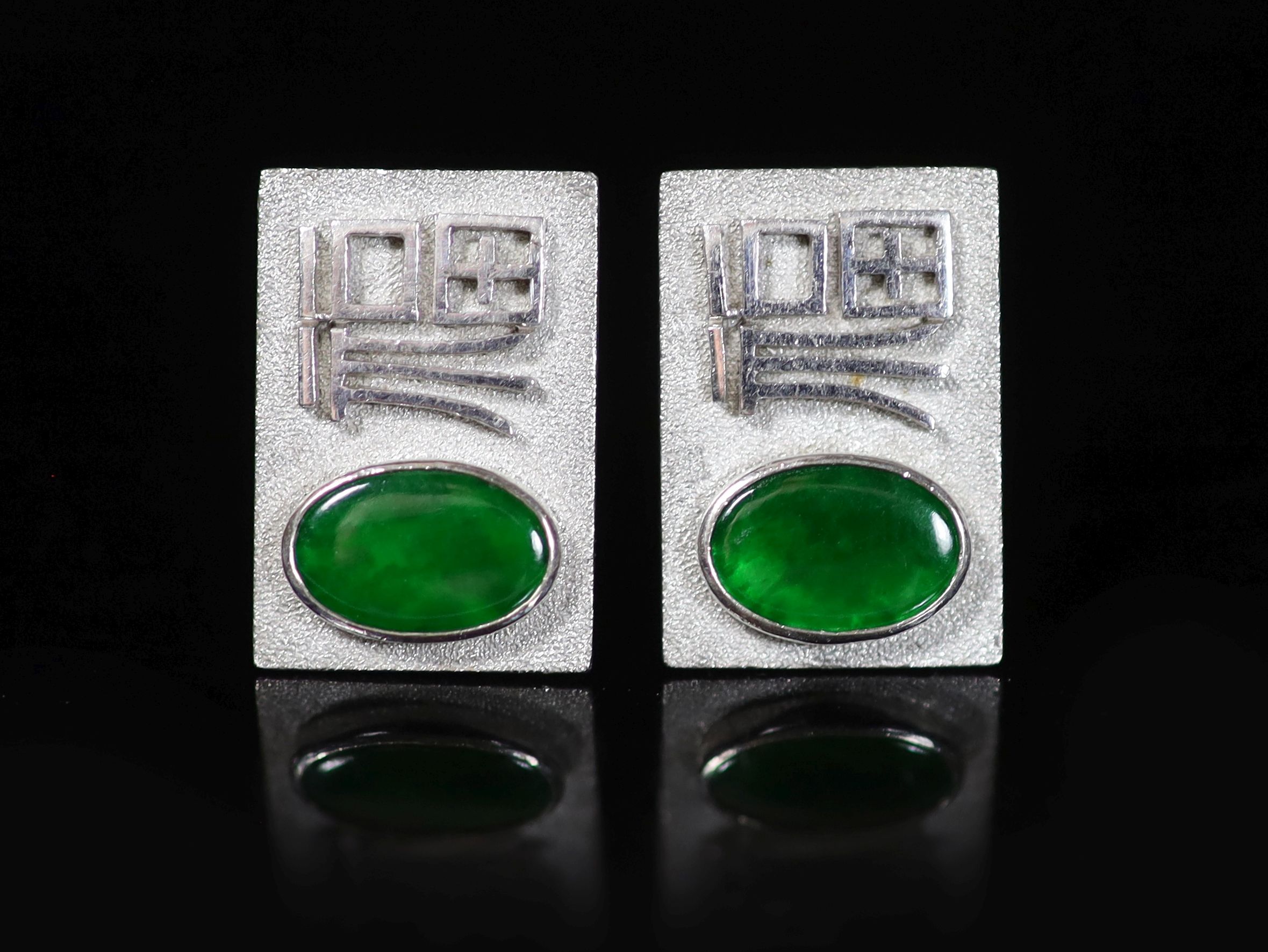 A pair of Chinese 14K white gold ‘Fu’ cufflinks set with oval green jade plaques,